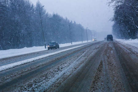 snowfall and fog on winter highway in twilightの写真素材