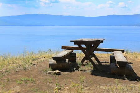 wooden table and bench on bank of lake Turgoyak Ural Russiaの写真素材