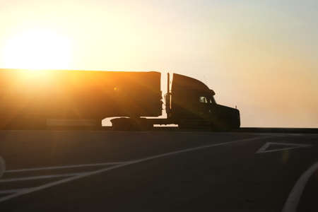 truck goes on highway in evening on sunsetの写真素材