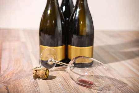 bottles with red wine stopper and an empty wine glassの写真素材