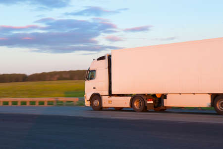 big truck goes on highway to sunsetの写真素材