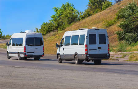 white minibuses go on the twisting road in the summerの写真素材