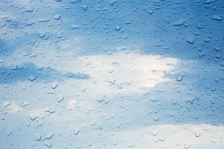 rain drops on glass against the cloudy skyの写真素材