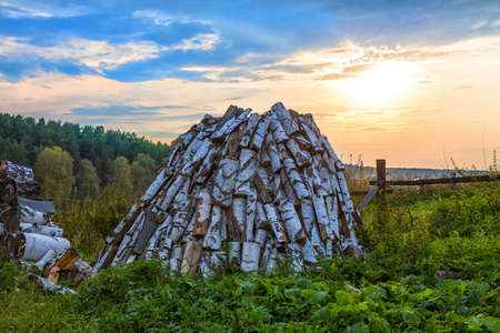 sunset in the village with a woodpile in the foreground