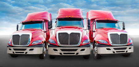 Three large red truck on the roadの写真素材