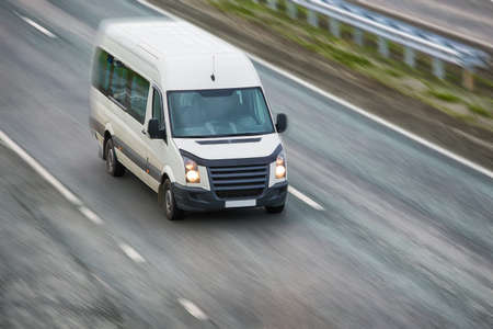 small white bus goes on highway in eveningの写真素材