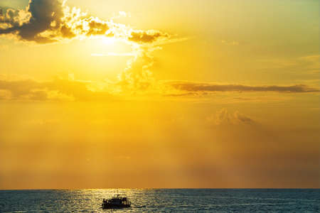 Boat with people in the sea at sunsetの写真素材