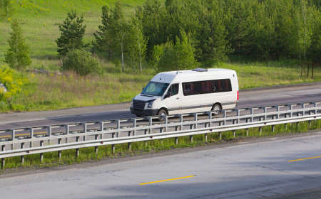 minibus goes on the country highway along the woodの写真素材