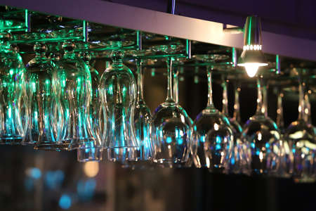 glasses hanging on an arm over a bar counterの写真素材