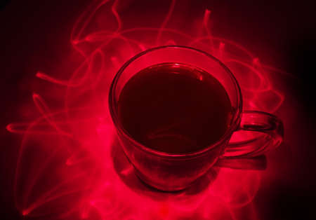 glass coffee mug in the rays of the red laserの写真素材
