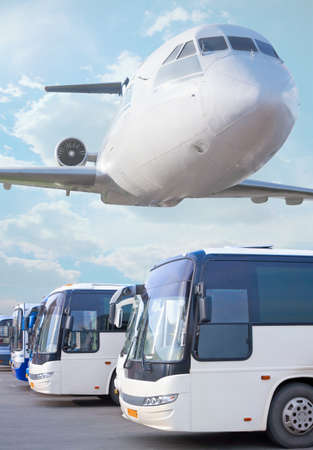 plane flying in sky over buses going in cityの写真素材