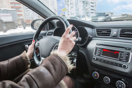 female hands on the steering wheel of car in winter