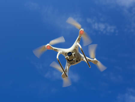 flying drone with camera in blue skyの写真素材