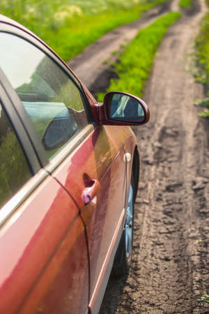 red car on country road on summer meadowの写真素材