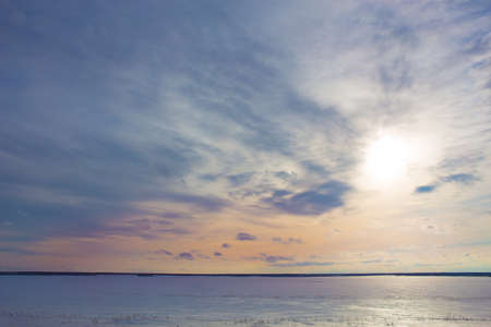 beautiful sunset over the lake covered with ice in winterの写真素材