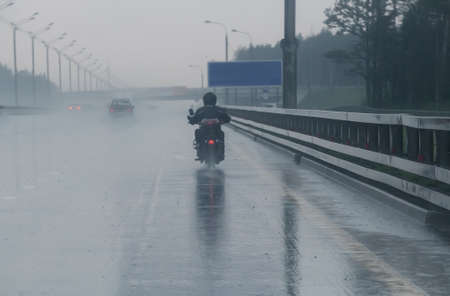 motorcyclist moves on motorcycle on highway to rainy weatherの写真素材