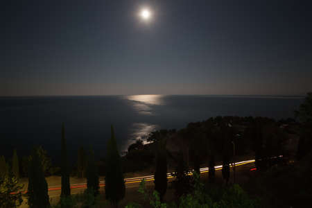 Seashore highway, horizon sky and moon at nightの写真素材
