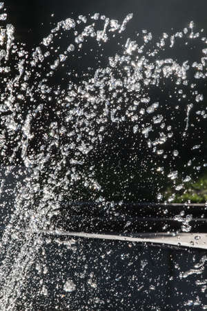 Fountain of drops of water on dark background closeup