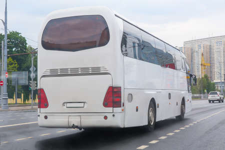 white tourist bus goes on the city streetの写真素材