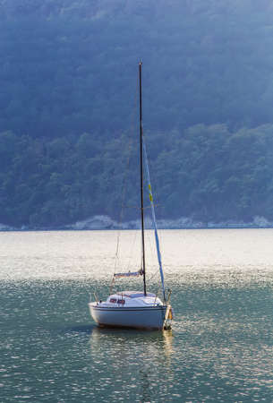 Sailing yacht on beautiful lake amidst wooded mountainsの写真素材