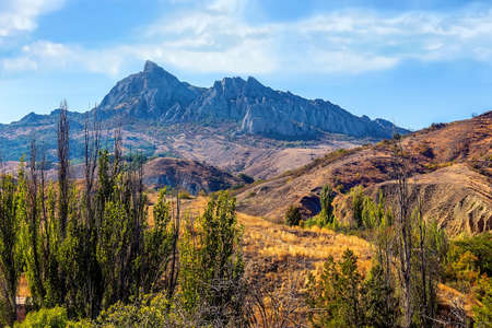 Mountain forest landscape under evening sky with clouds in sunlightの写真素材