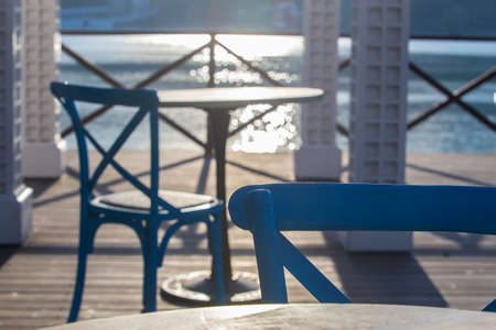 Cafe outside with wooden table and chair by the sea in the morning at sunriseの写真素材