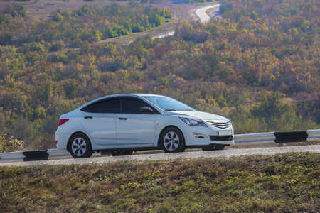 Car drives along the mountainous, winding highway in autumn