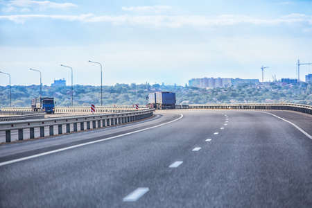 Trucks go on a new highway against the backdrop of the city panoramaの写真素材