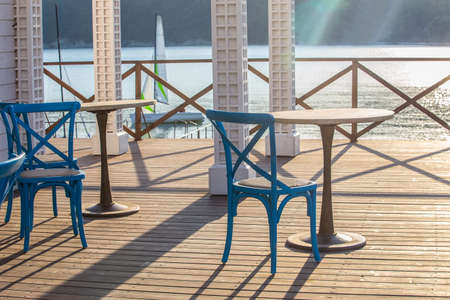 Cafe outside with wooden table and chair by the sea in the morning at sunriseの写真素材