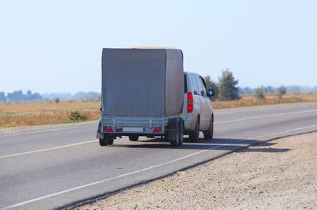 car with the trailer goes on country highway