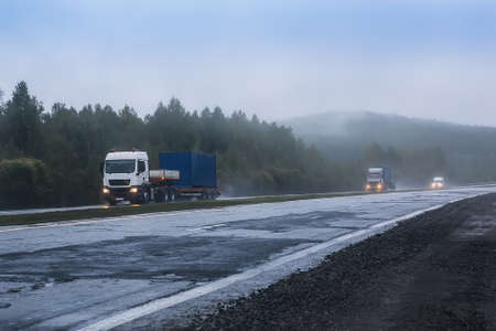 trucks with containers go in the fog along the country roadの写真素材