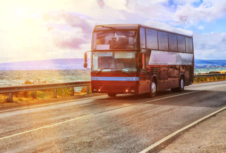 tourist bus is moving along the highway near the sea shoreの写真素材