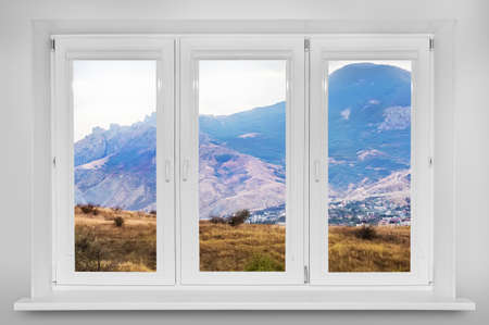 View from the window. Mountain forest landscape under evening sky with clouds in sunlight