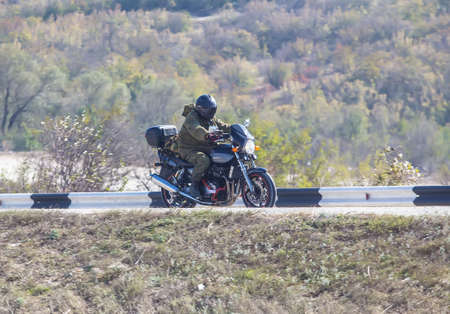 Motorcyclist in helmet rides along the road against hilly background.の写真素材