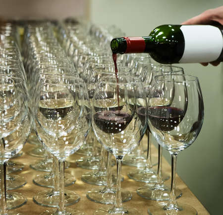 row of wine glasses and a bottle of red wine. Preparation for a banquet.の写真素材