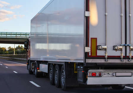 Truck with semitrailer moves along a country road. Back view.の写真素材