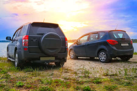 two cars on the shore of the lake at sunsetの写真素材