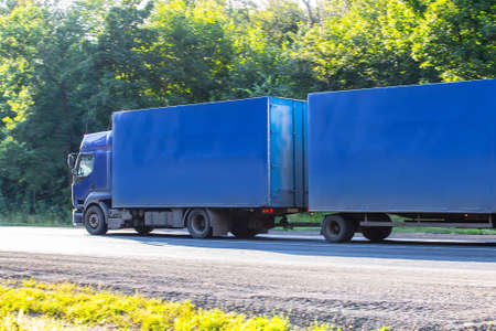 truck with the trailer is moving along the highway along the forestの写真素材