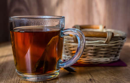 glass mug with tea and wicker basket on the tableの写真素材
