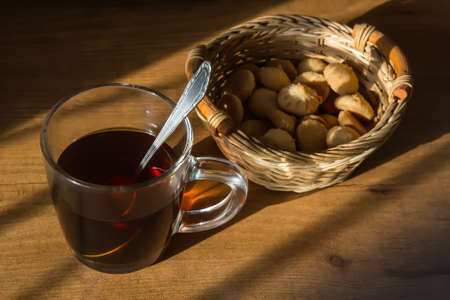 glass mug with tea and wicker basket on the tableの写真素材