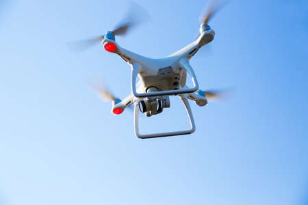flying drone with camera in blue skyの写真素材