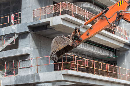 excavator on the construction of a modern concrete buildingの写真素材