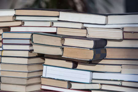 A stack of old and new books of different sizes and shapes stacked in a chaotic manner. Close-up.の写真素材