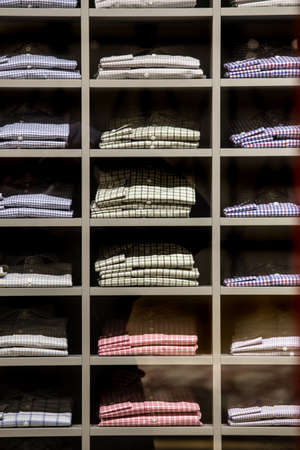 Variety of checkered casual men's shirts on closet shelves.の写真素材