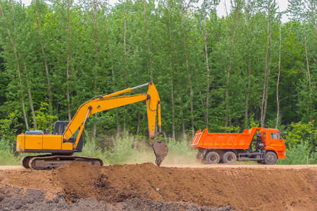 excavator and dump truck on the construction of a country highway