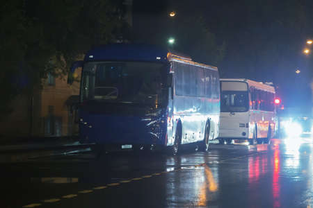 buses on the street at night in the rain in the city