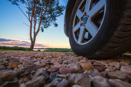 close-up of the left front wheel of the car view from below against the background of the evening...