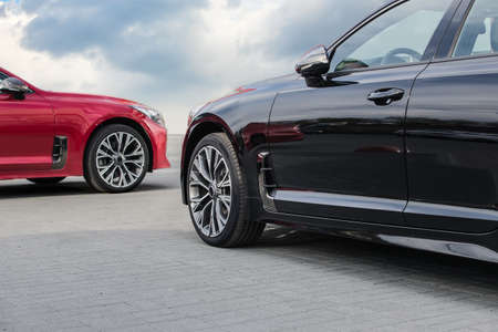 luxury red and black cars against the blue cloudy sky