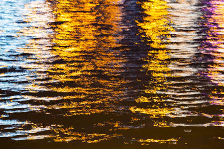 colored glare of light on the surface of the river at night in the cityの写真素材