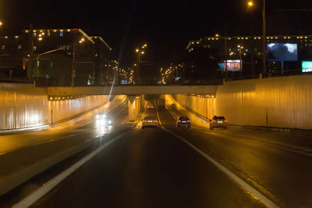Cars drive through the viaduct at night. Night city life.